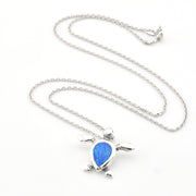 Silver turtle pendant with blue stone on a chain against a white background