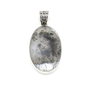 An oval pendant featuring a gray and black mottled stone, set in a polished silver bezel with an ornate silver bail, shown on a plain white background.