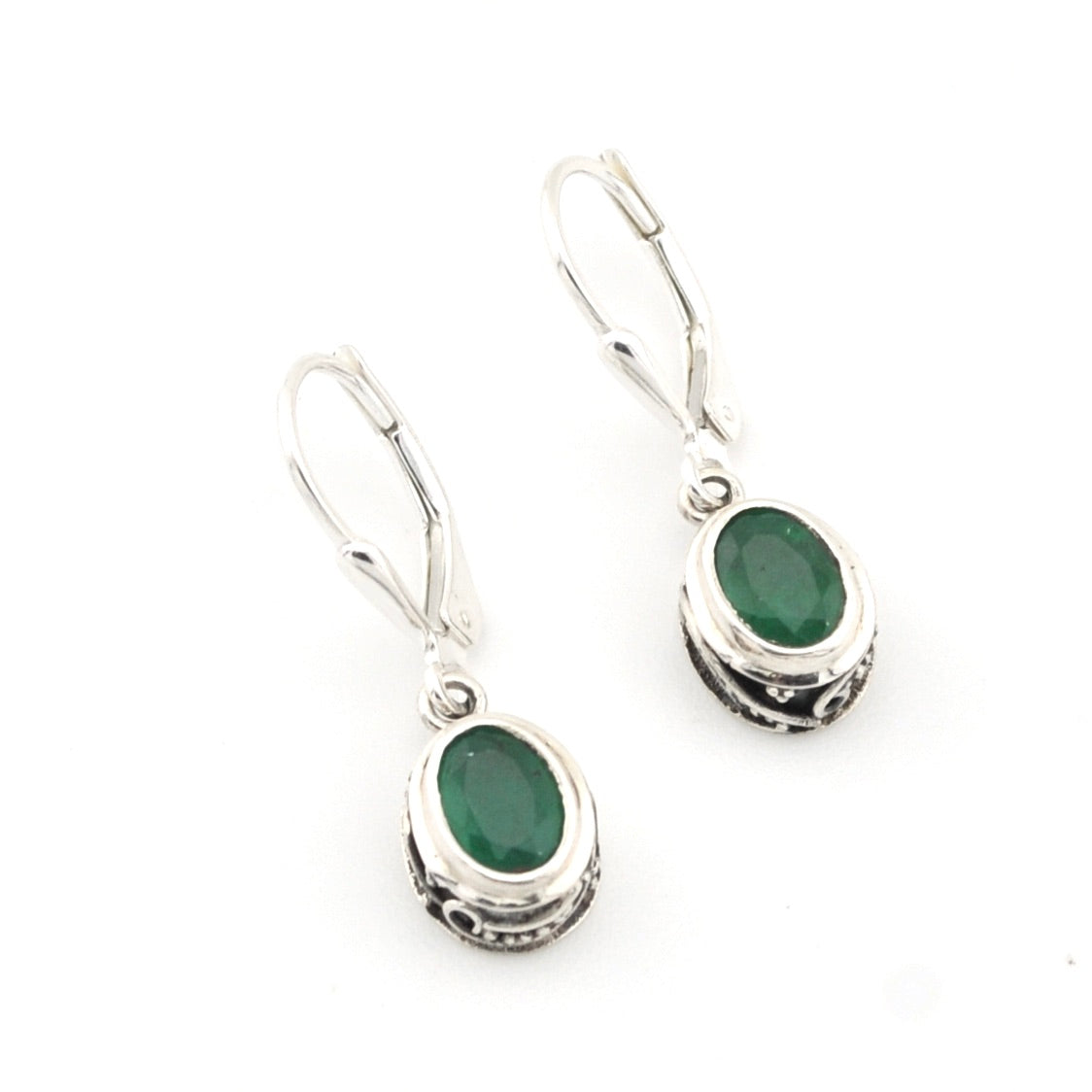 Silver earrings with green gemstones on a white background