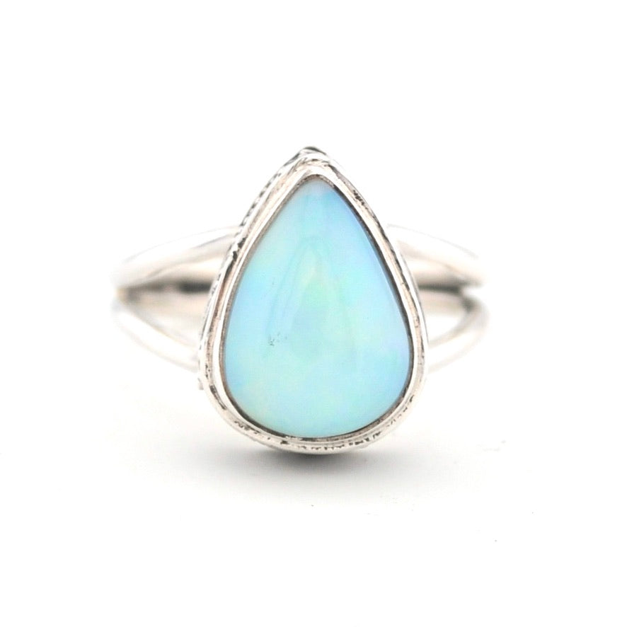 Silver ring with a teardrop-shaped light blue gemstone on a white background