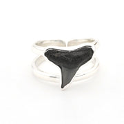 Silver ring with a black shark tooth on a white background