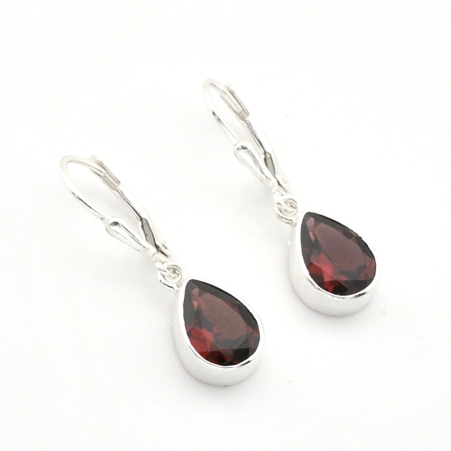 A pair of silver leverback drop earrings featuring faceted teardrop-shaped dark red gemstones in polished silver bezel settings, shown on a plain white background.