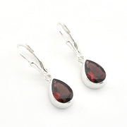 A pair of silver leverback drop earrings featuring faceted teardrop-shaped dark red gemstones in polished silver bezel settings, shown on a plain white background.