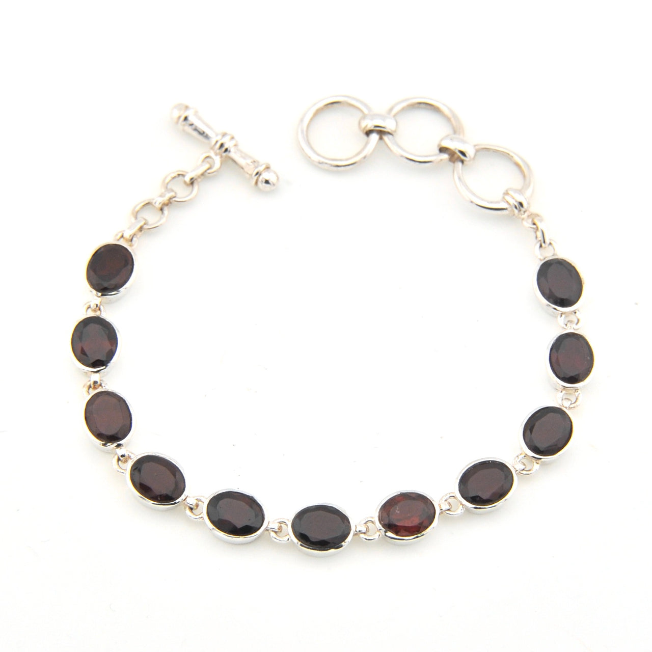 Silver bracelet with dark gemstones on a white background