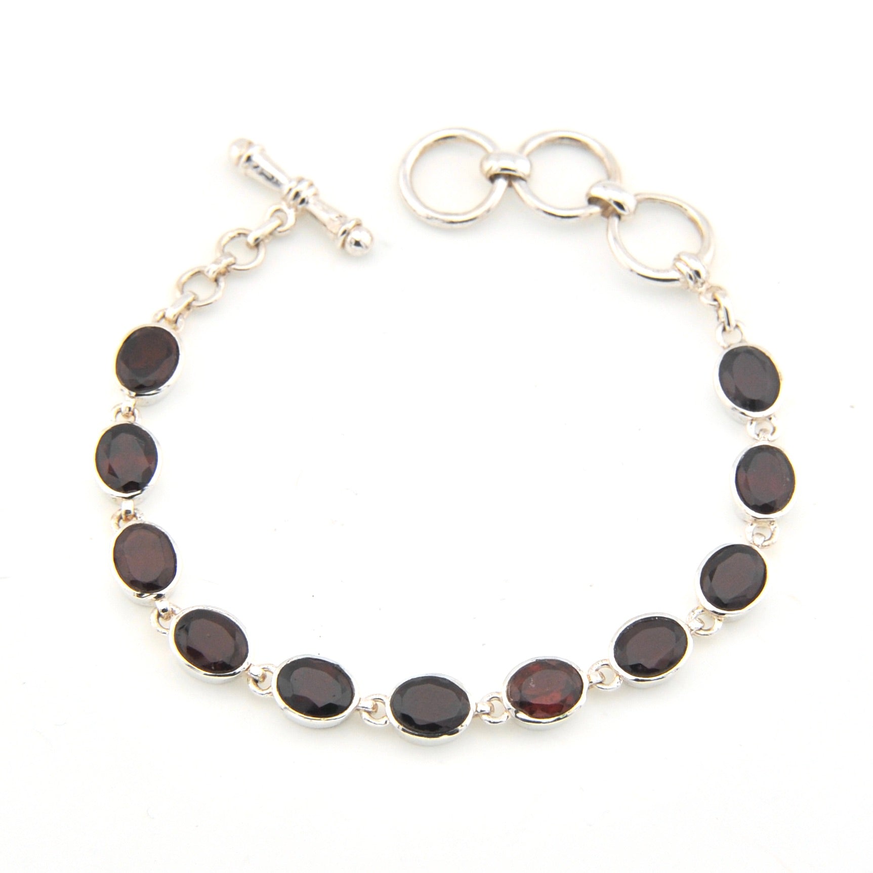 Silver bracelet with dark gemstones on a white background