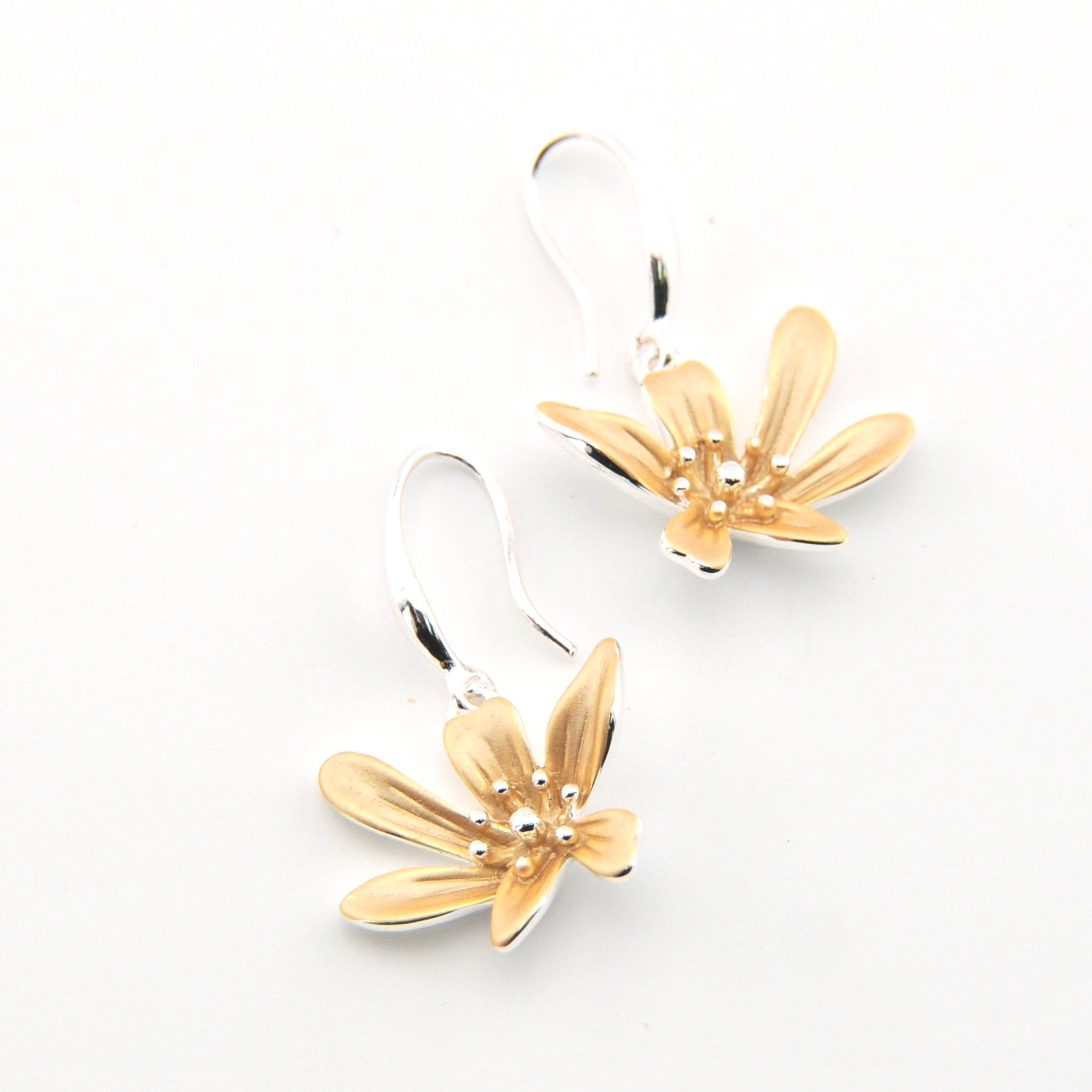 Pair of gold flower-shaped earrings on a white background
