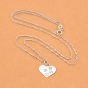 Silver necklace with a heart-shaped pendant featuring paw prints on a beige background