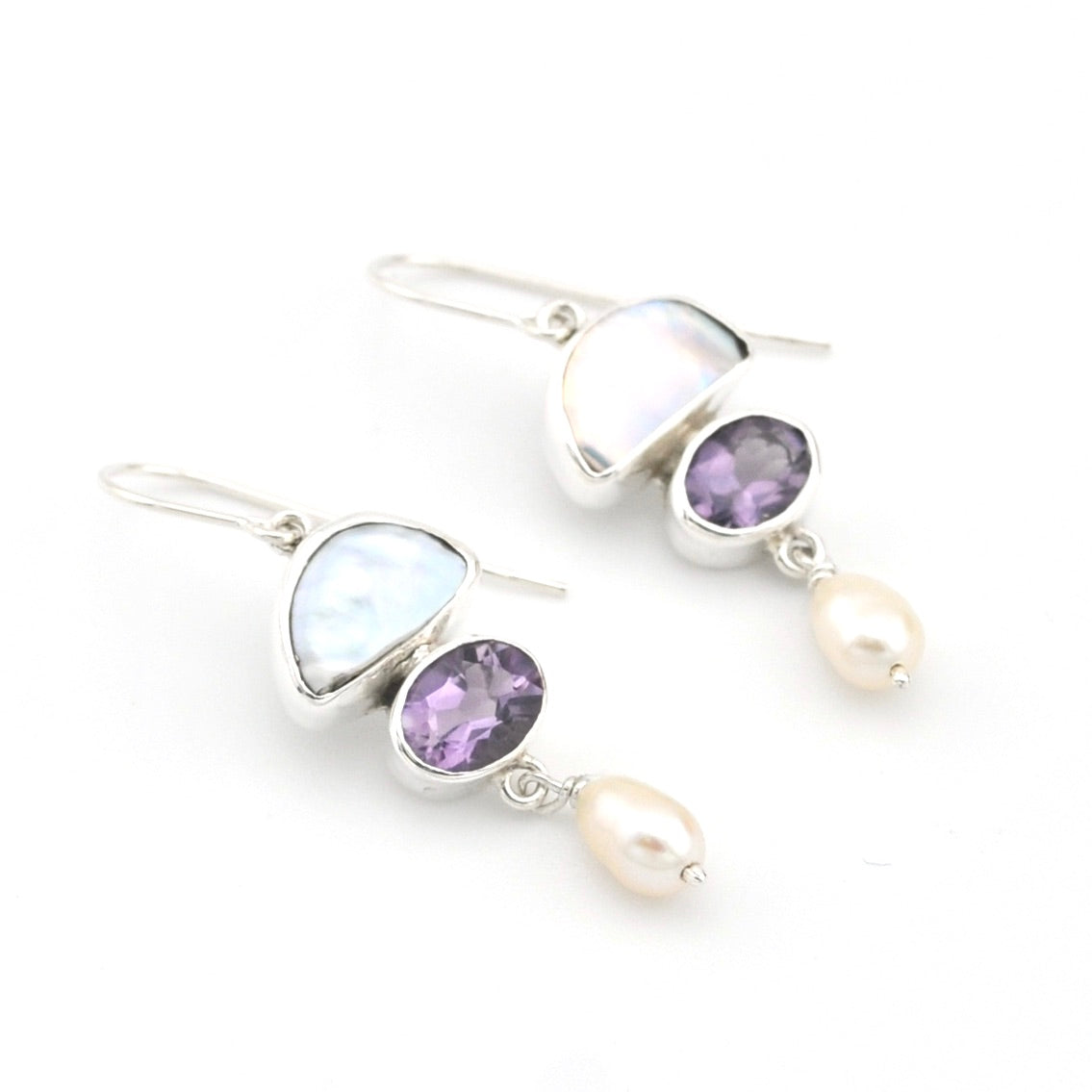 Silver earrings with purple gemstones and pearls on a white background