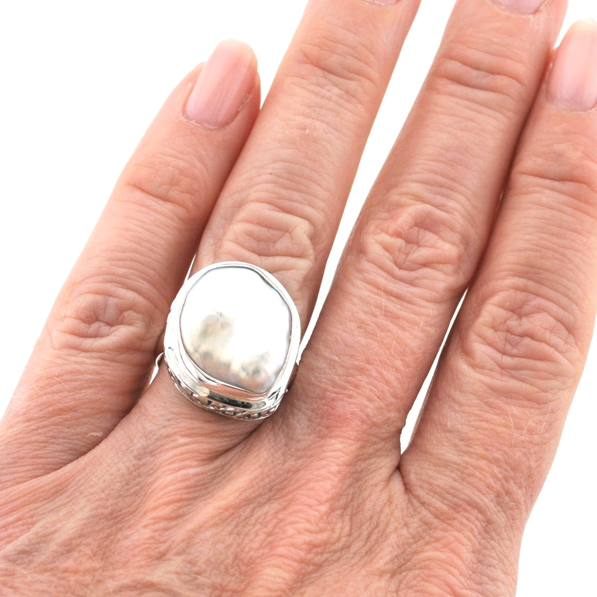 A silver ring with a large, irregularly shaped polished white stone, shown worn on a person's finger against a plain white background.