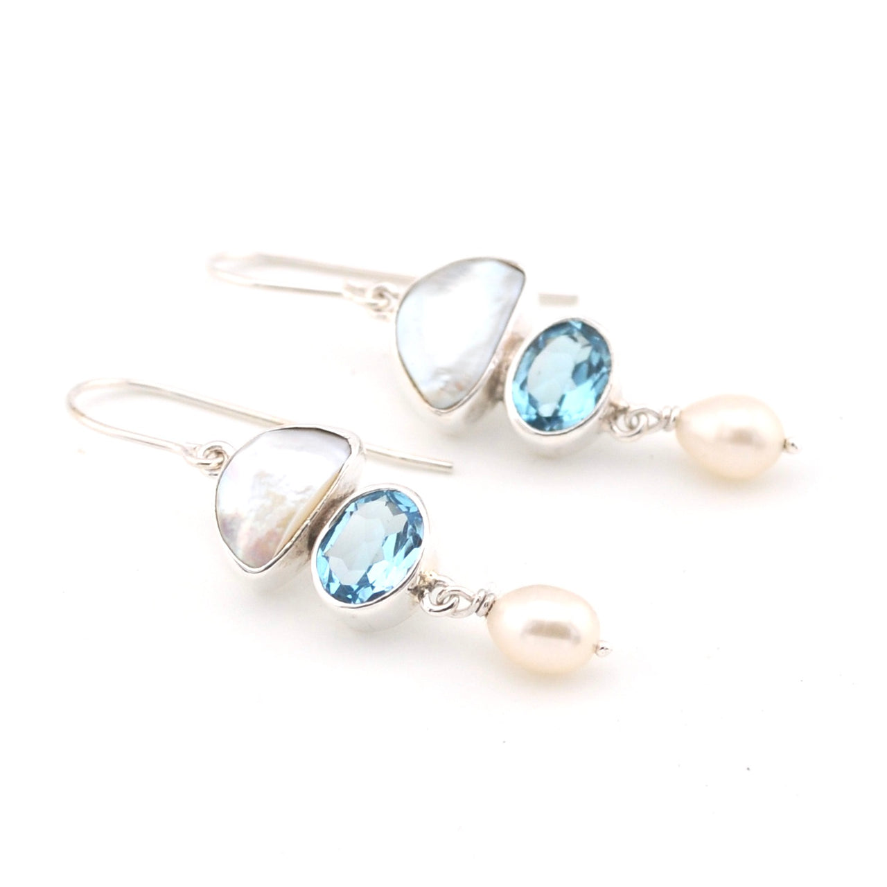 Pair of earrings with blue gemstones and pearls on a white background