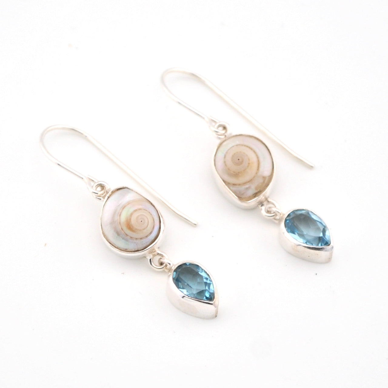 Pair of earrings with shell and blue gemstone drops on a white background