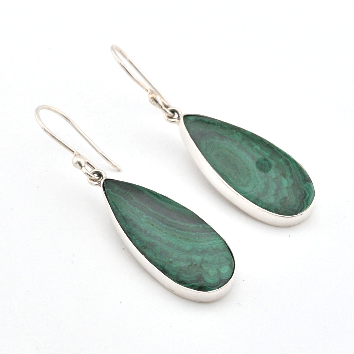 Teardrop-shaped green earrings with silver hooks on a white background