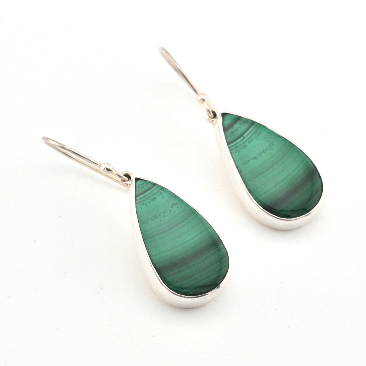 Teardrop-shaped green earrings with silver hooks on a white background
