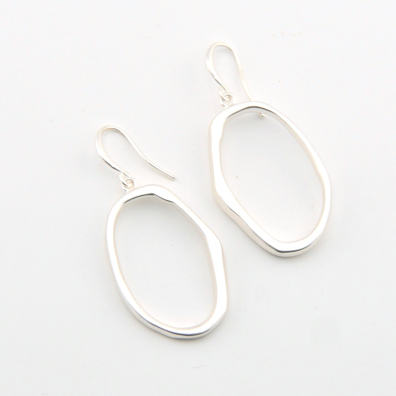 Silver oval earrings on a light gray background