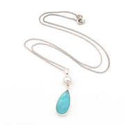 Necklace with a blue teardrop pendant and pearl on a white background