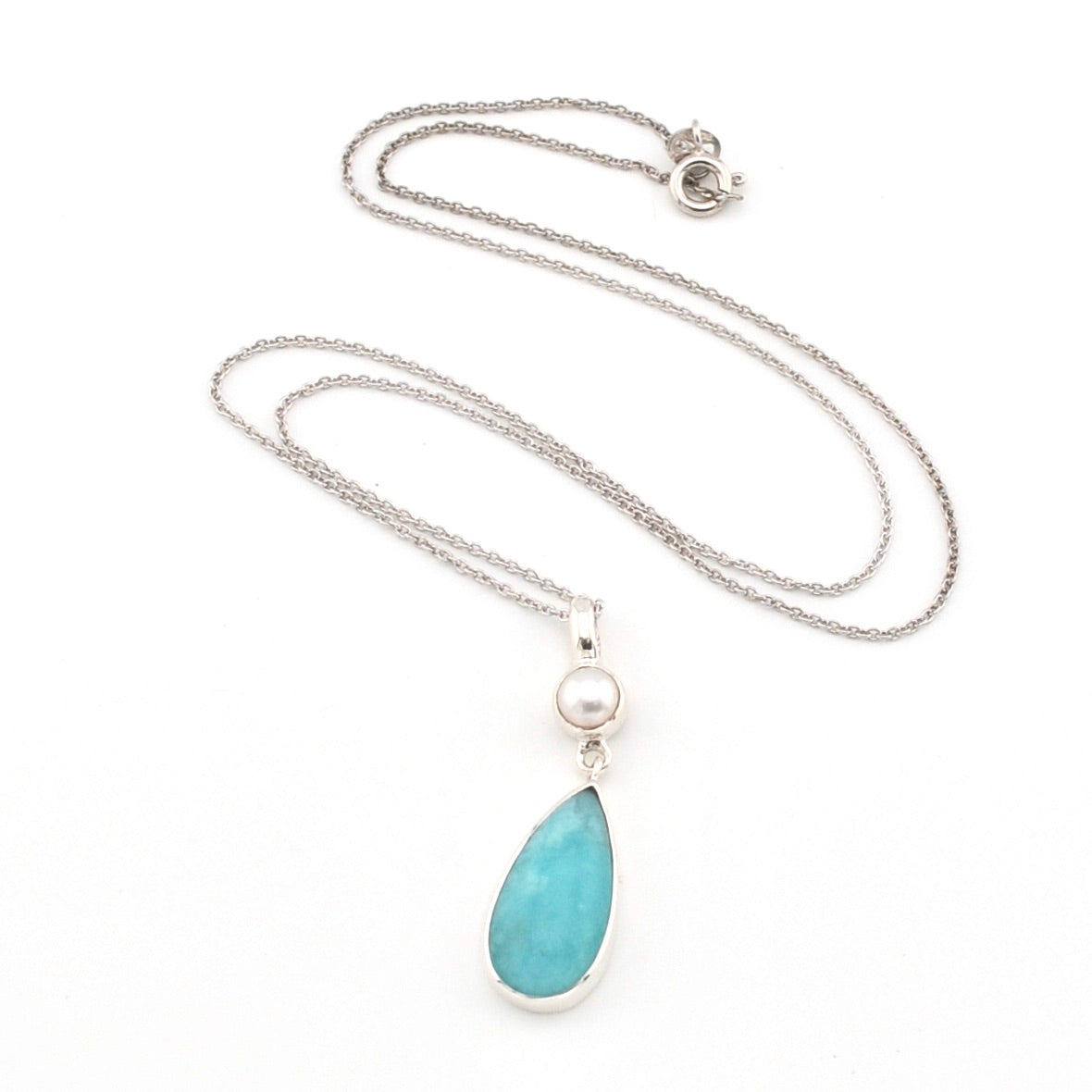 Necklace with a blue teardrop pendant and pearl on a white background