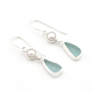 A pair of silver drop earrings featuring a small white pearl and a teardrop-shaped light blue-green sea glass stone, shown on a clean white background.
