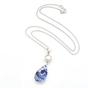 A silver chain necklace featuring a teardrop-shaped pendant with a blue and white marbled pattern, accented by a small round white pearl, shown on a plain white background.