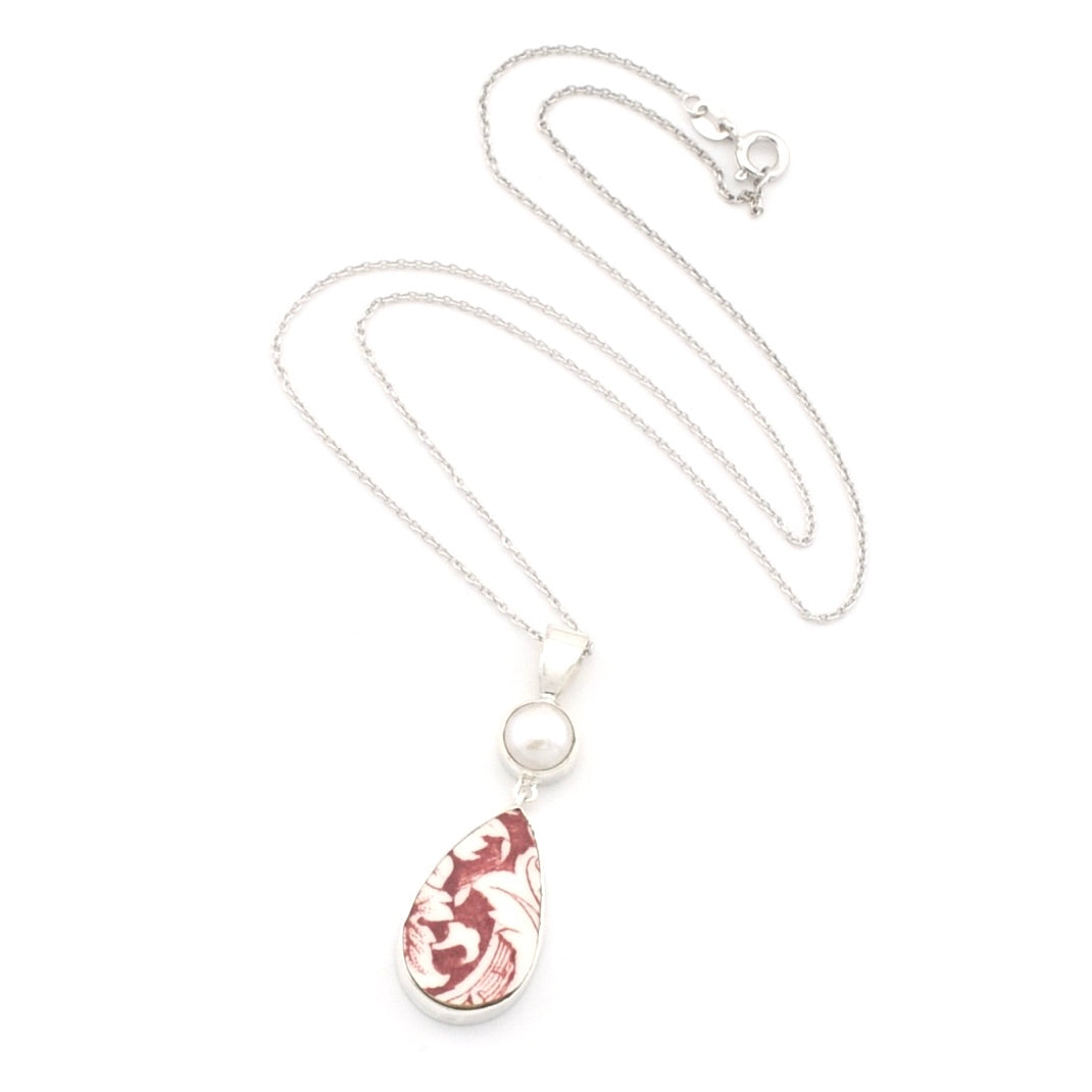 A silver teardrop pendant necklace featuring a white pearl and a marbled red and white teardrop charm, displayed on a clean white background.