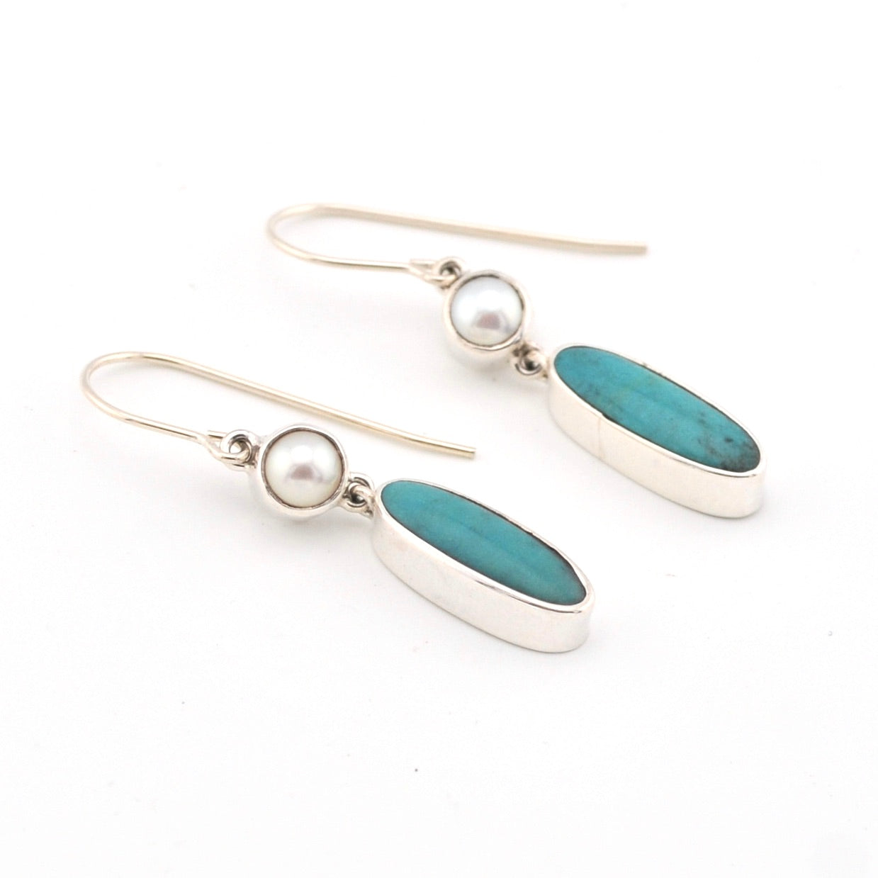 Pair of earrings with turquoise stones and pearls on a white background