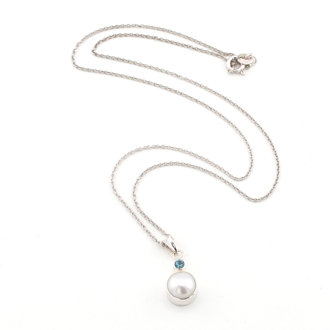 Pearl necklace with a blue gemstone on a white background