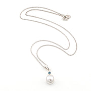 Pearl necklace with a blue gemstone on a white background