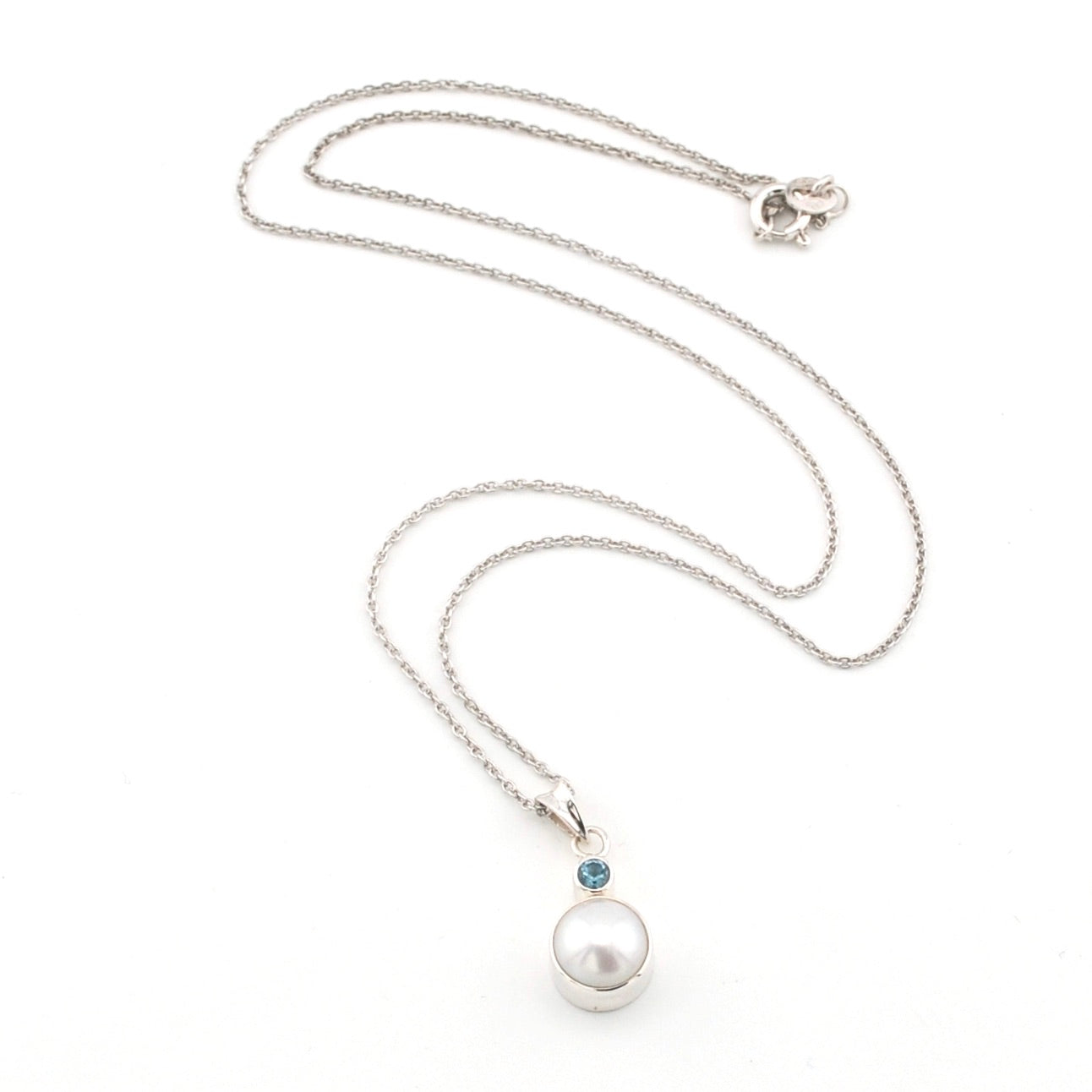Pearl necklace with a blue gemstone on a white background