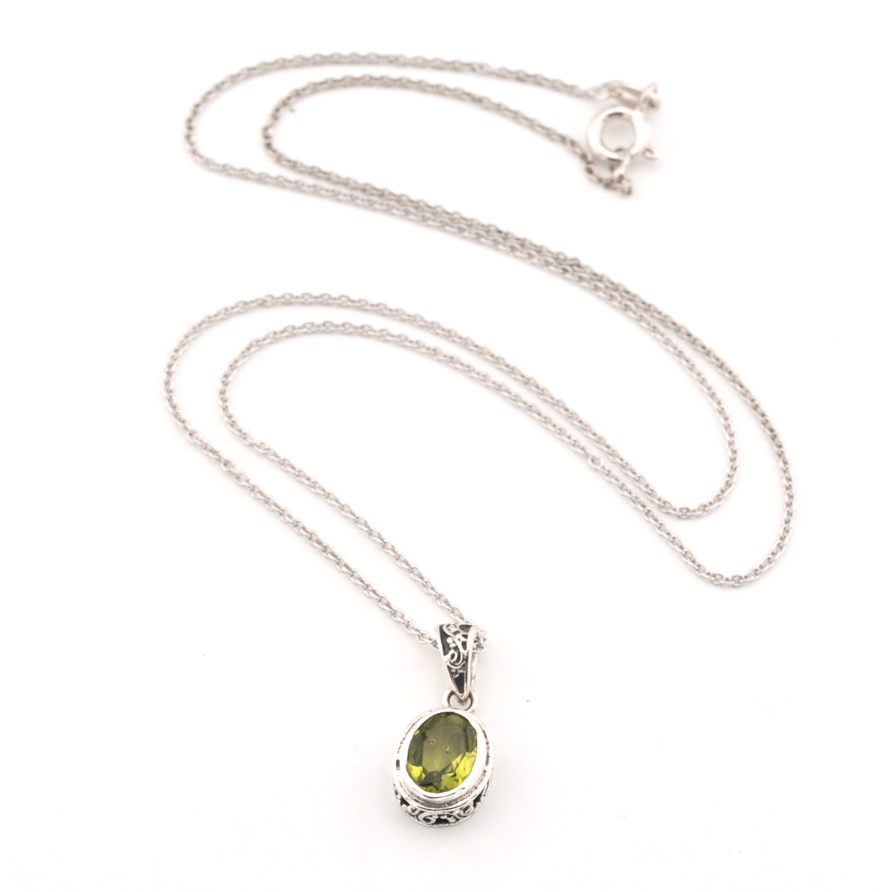 Silver necklace with a green peridot gemstone pendant on a white background