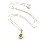 Silver necklace with a green peridot gemstone pendant on a white background