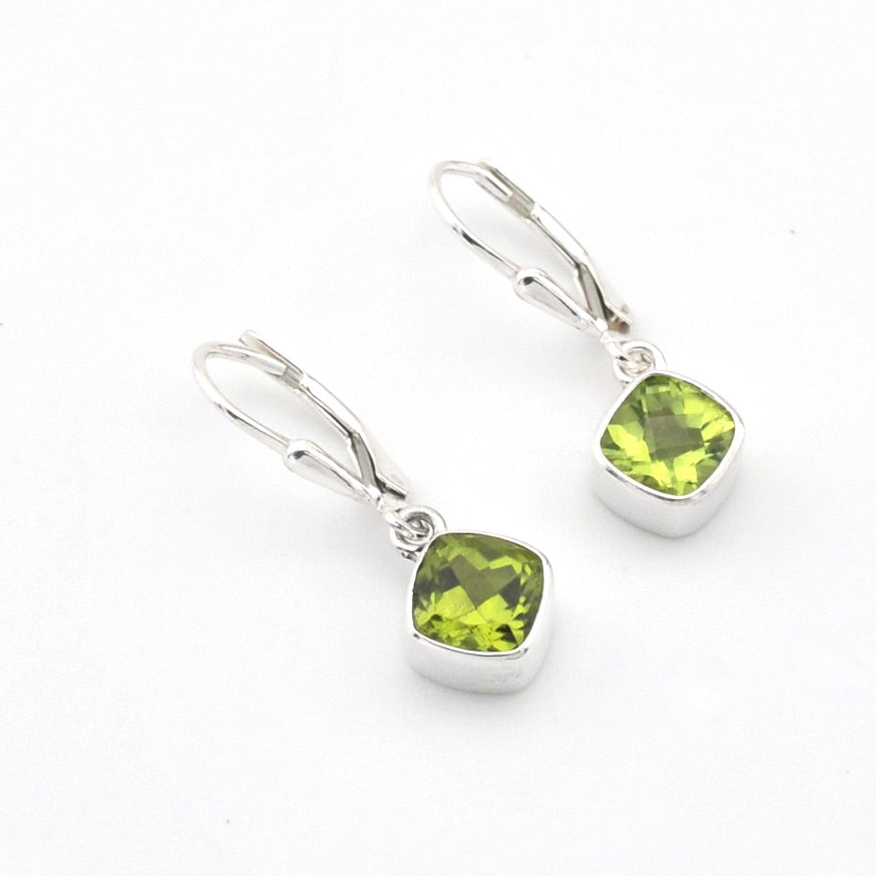 Silver earrings with green gemstones on a white background