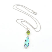 Necklace with a pendant featuring a green gemstone and abalone shell on a white background