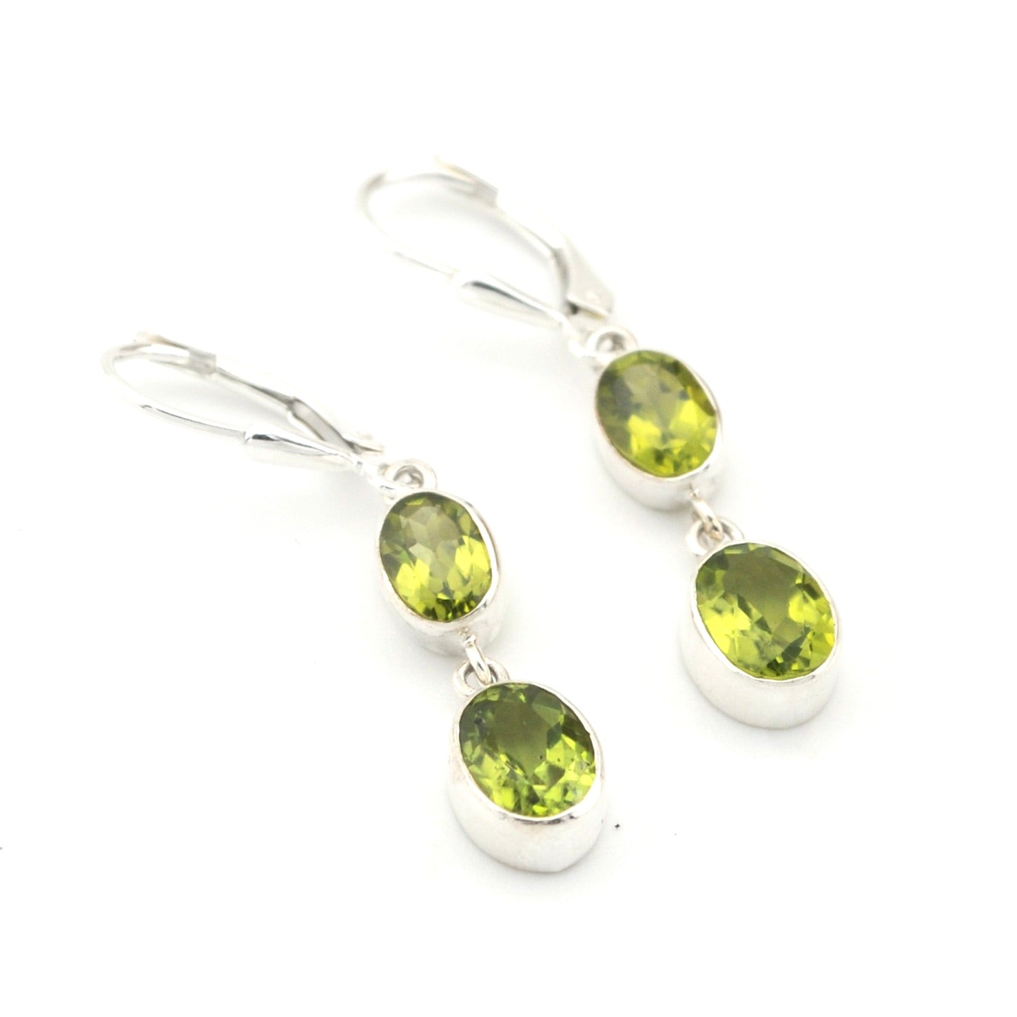 Pair of silver earrings with green gemstones on a white background