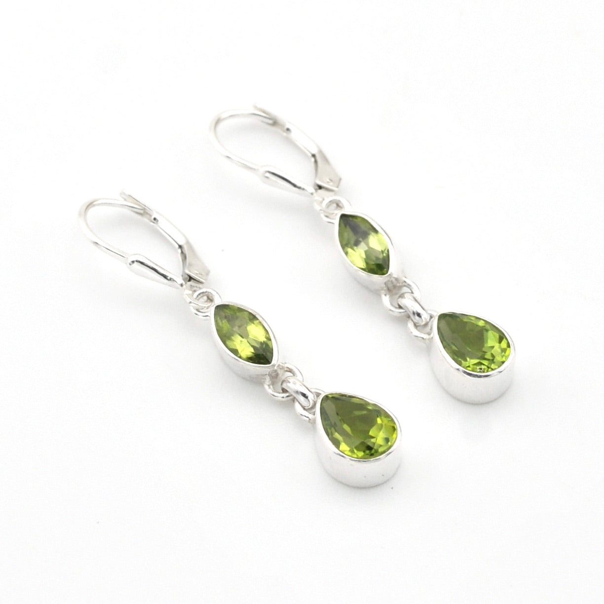 Pair of silver earrings with green gemstones on a white background