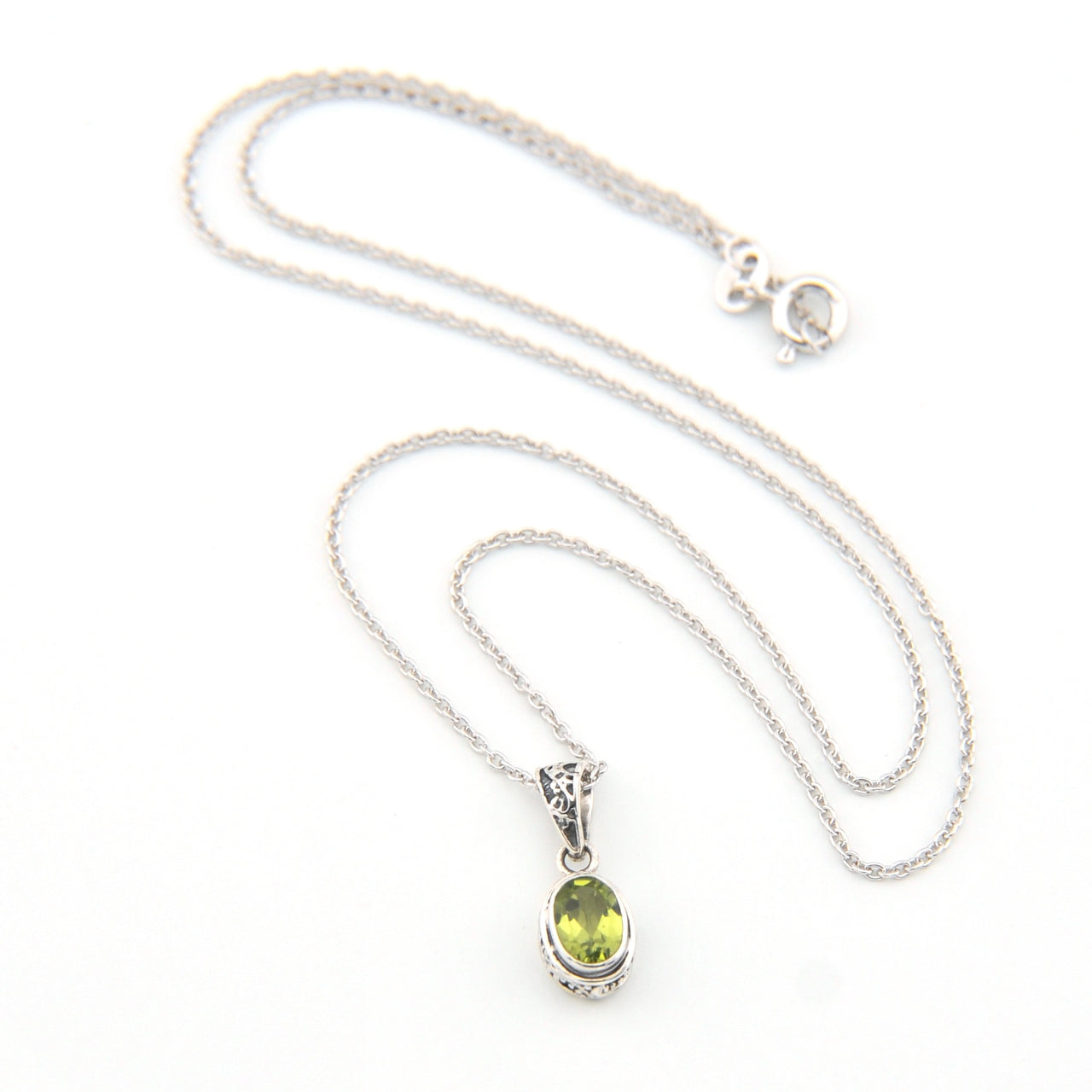 Silver necklace with a green pendant on a white background