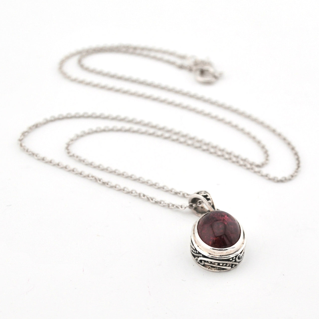 Silver necklace with a red gemstone pendant on a white background