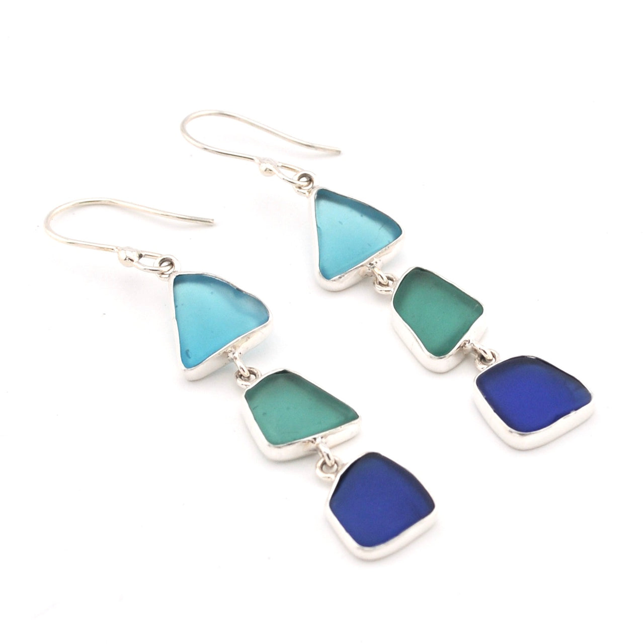 Pair of earrings with blue and green triangular glass on a white background