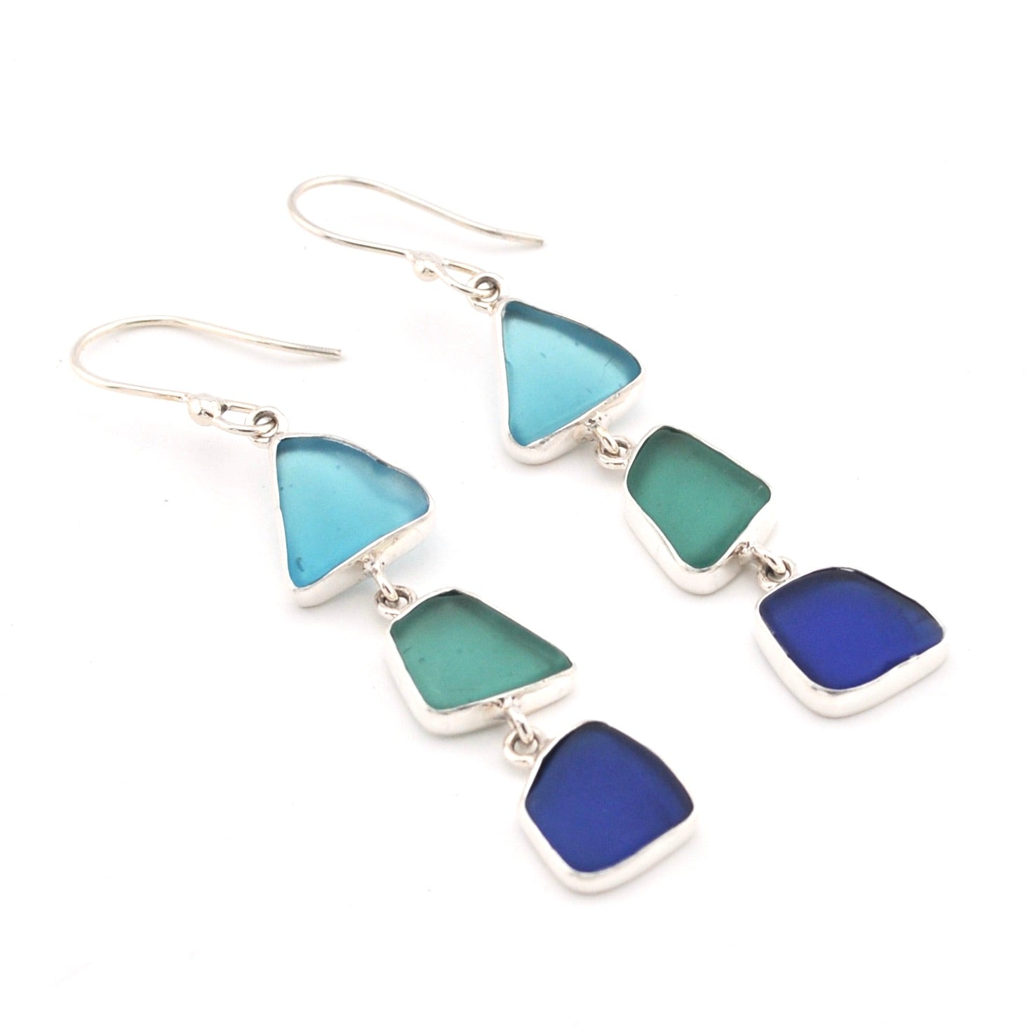 Pair of earrings with blue and green triangular glass on a white background
