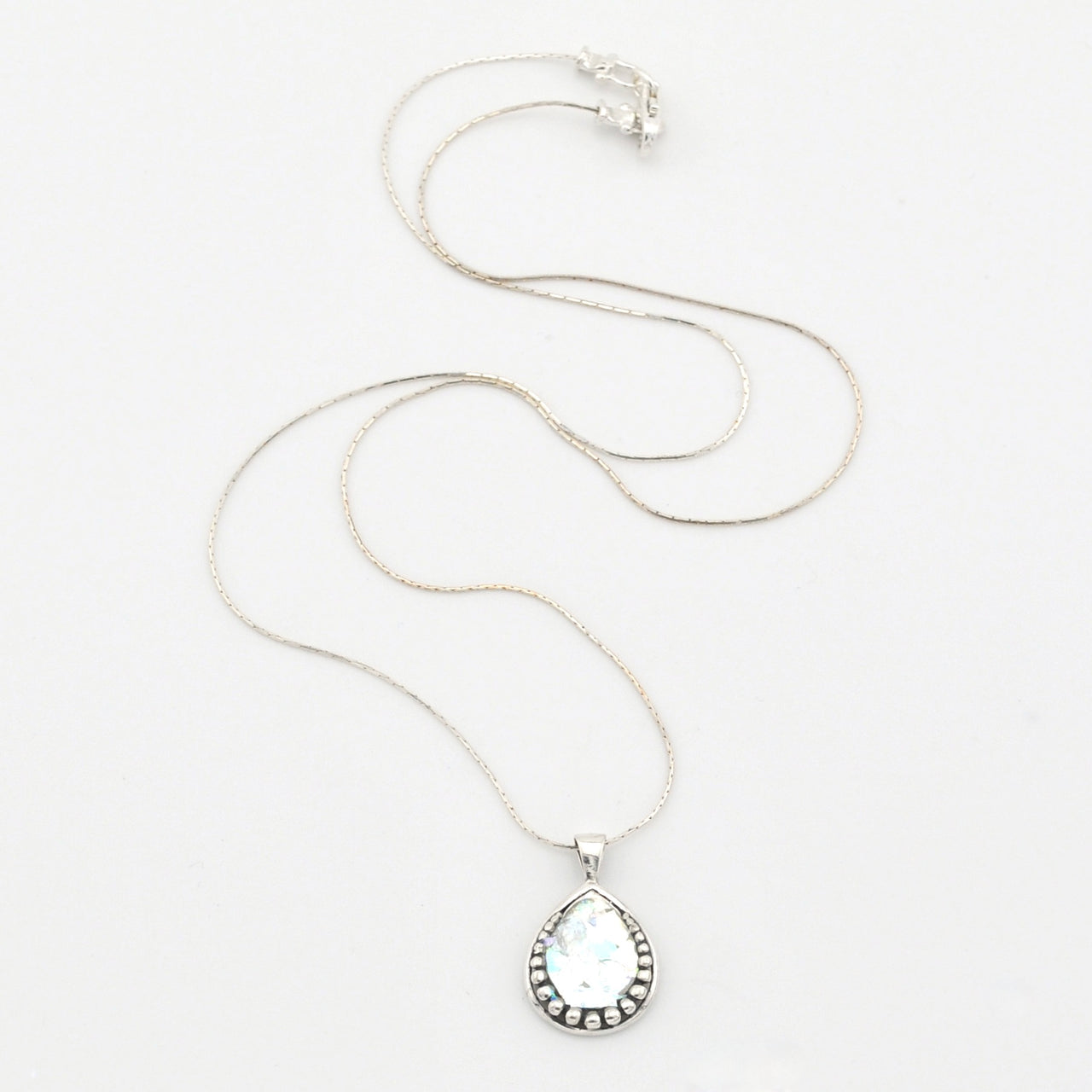 Silver necklace with a teardrop-shaped pendant on a white background
