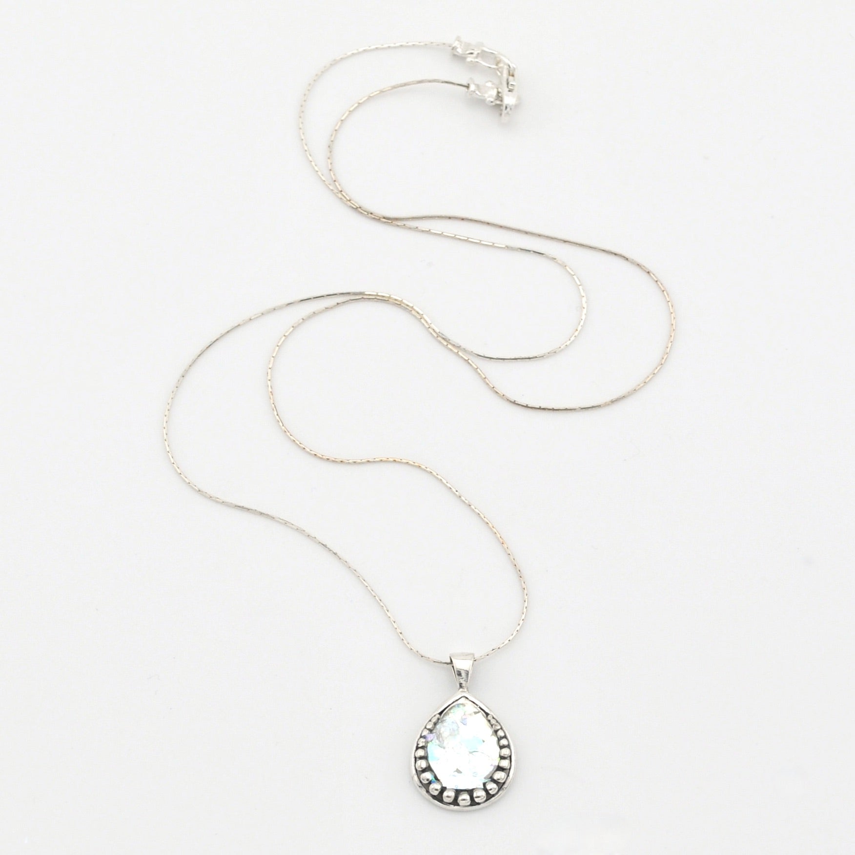 Silver necklace with a teardrop-shaped pendant on a white background