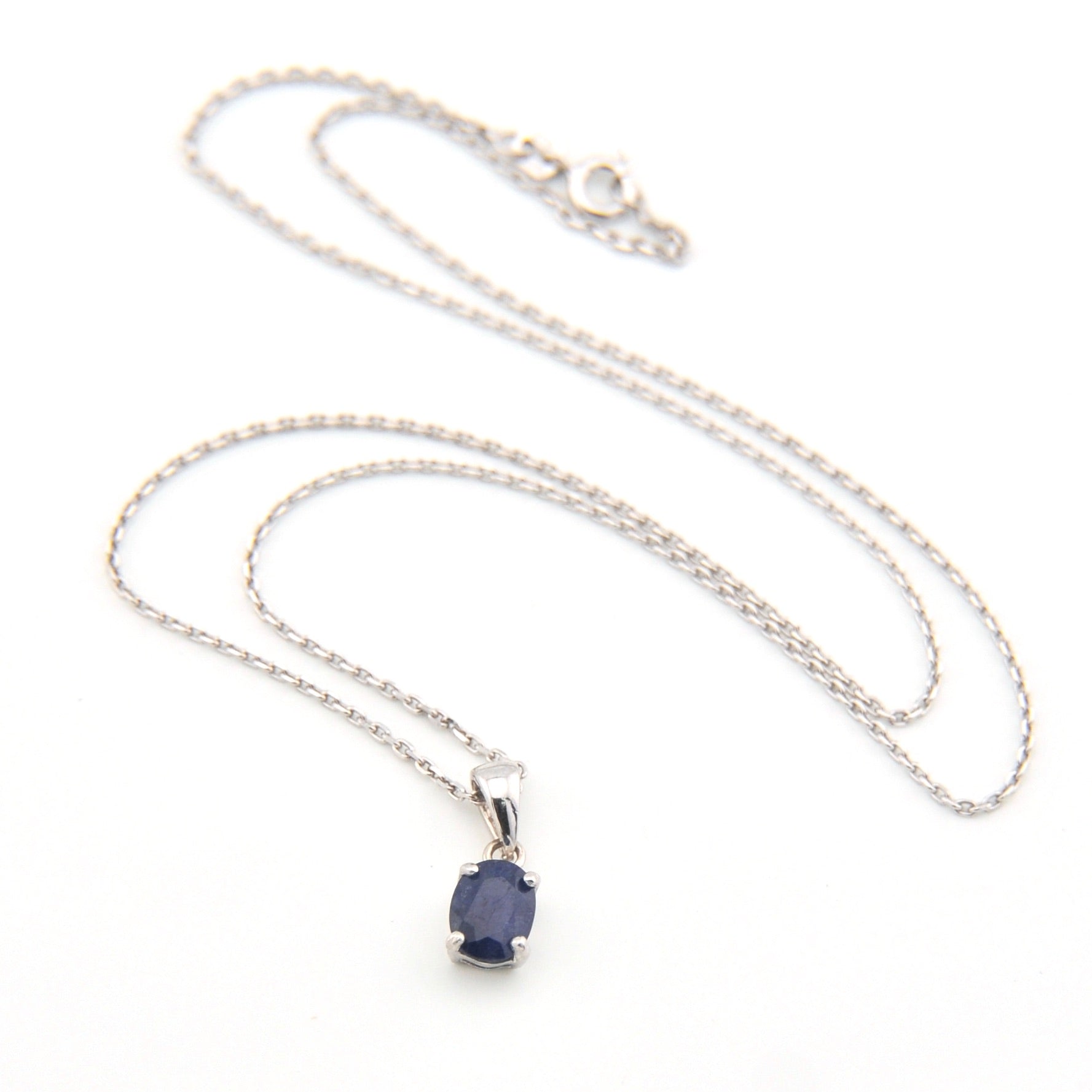 Silver necklace with a blue gemstone pendant on a white background