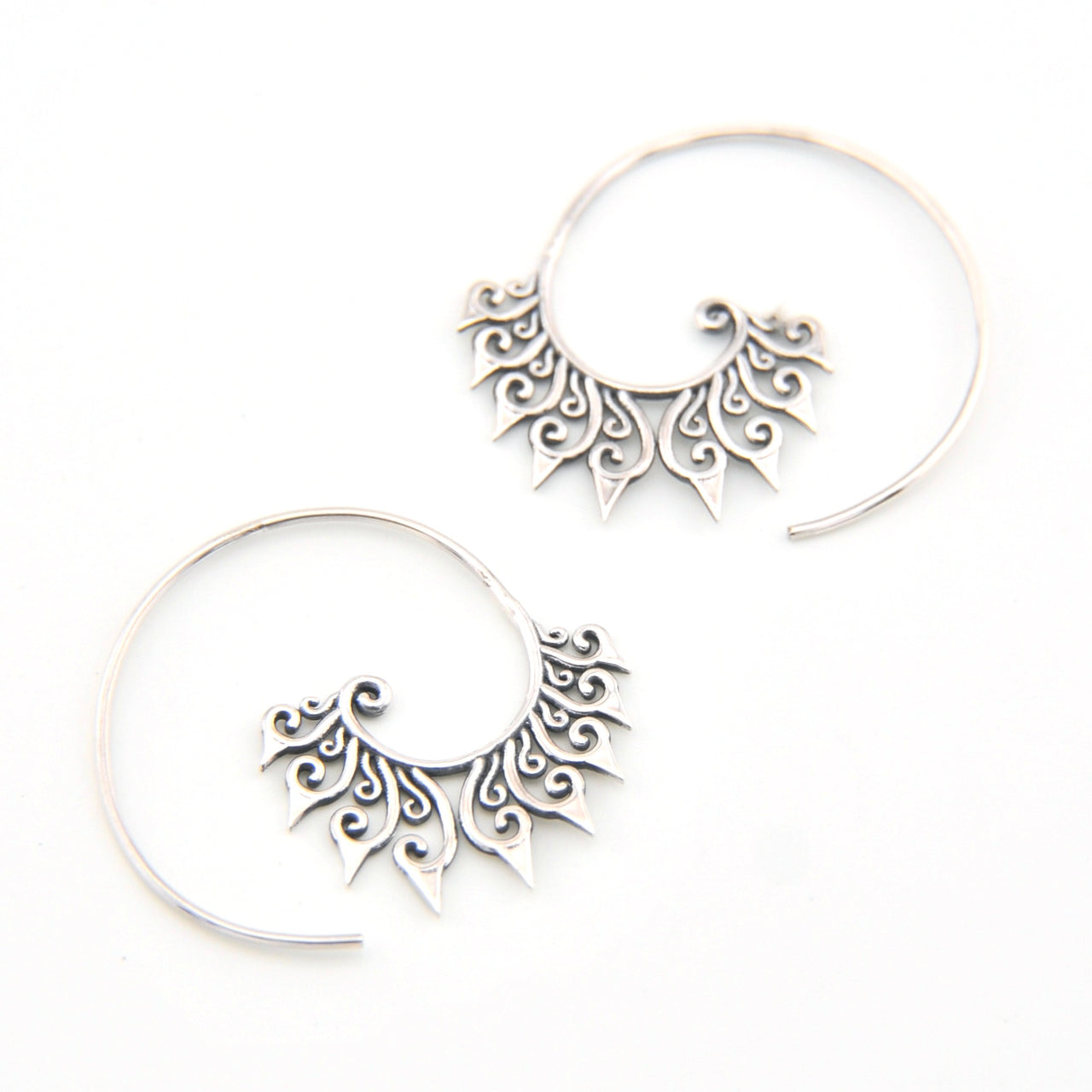 Pair of silver hoop earrings with intricate designs on a white background