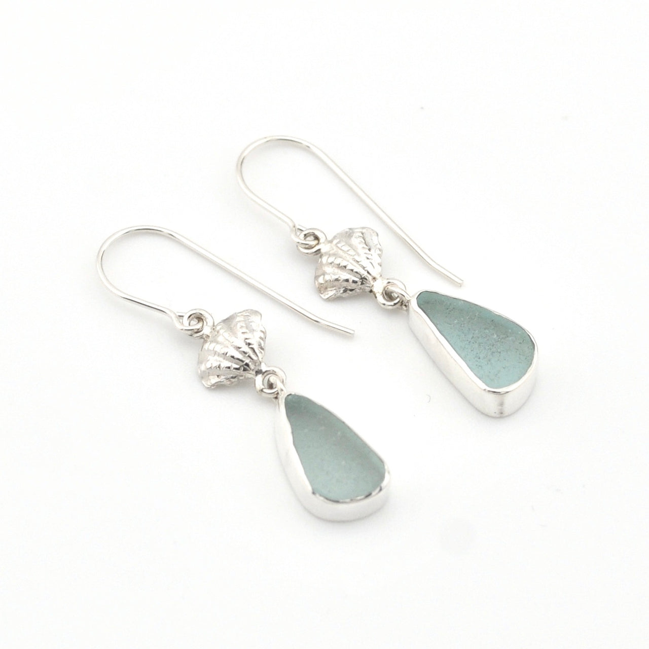 Silver earrings with teardrop-shaped sea glass on a white background