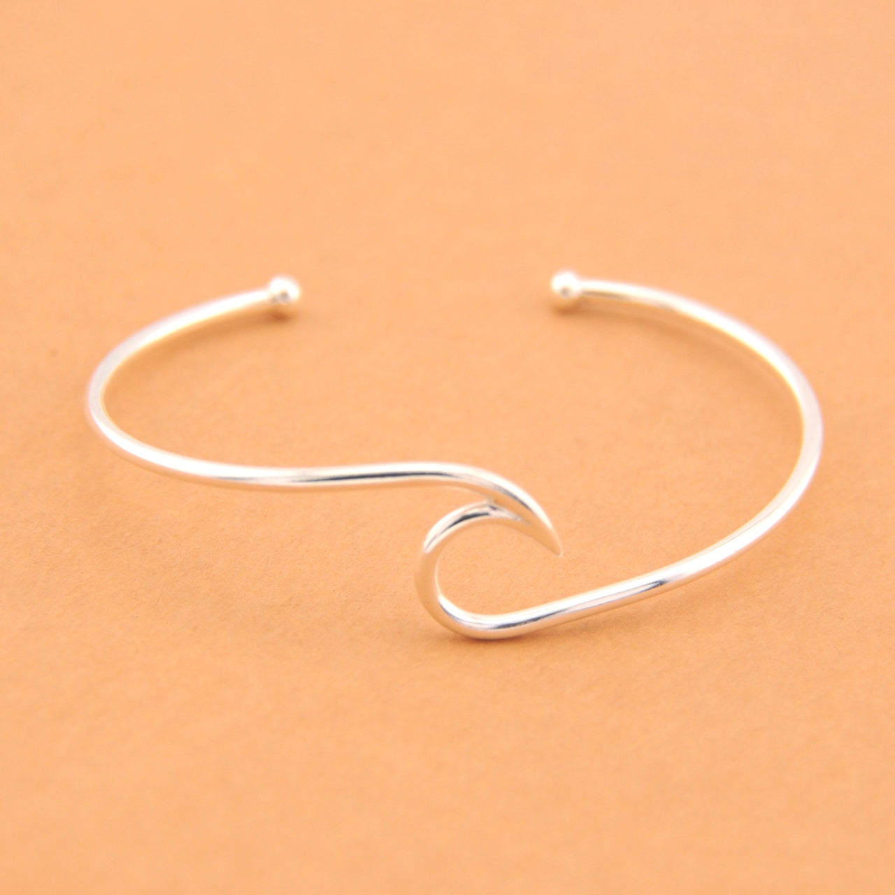 Silver wave-shaped bracelet on a beige background