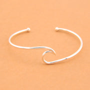 Silver wave-shaped bracelet on a beige background