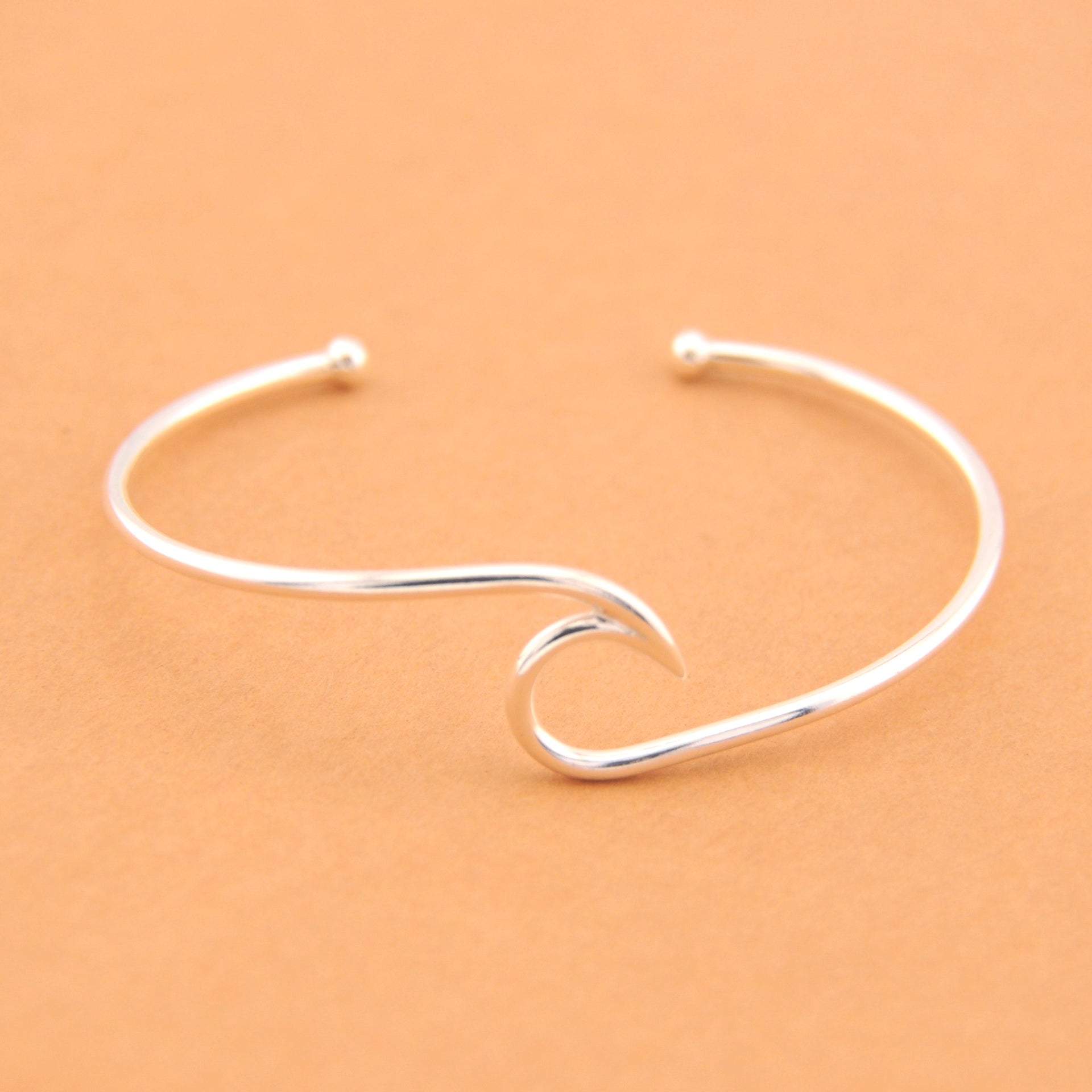 Silver wave-shaped bracelet on a beige background