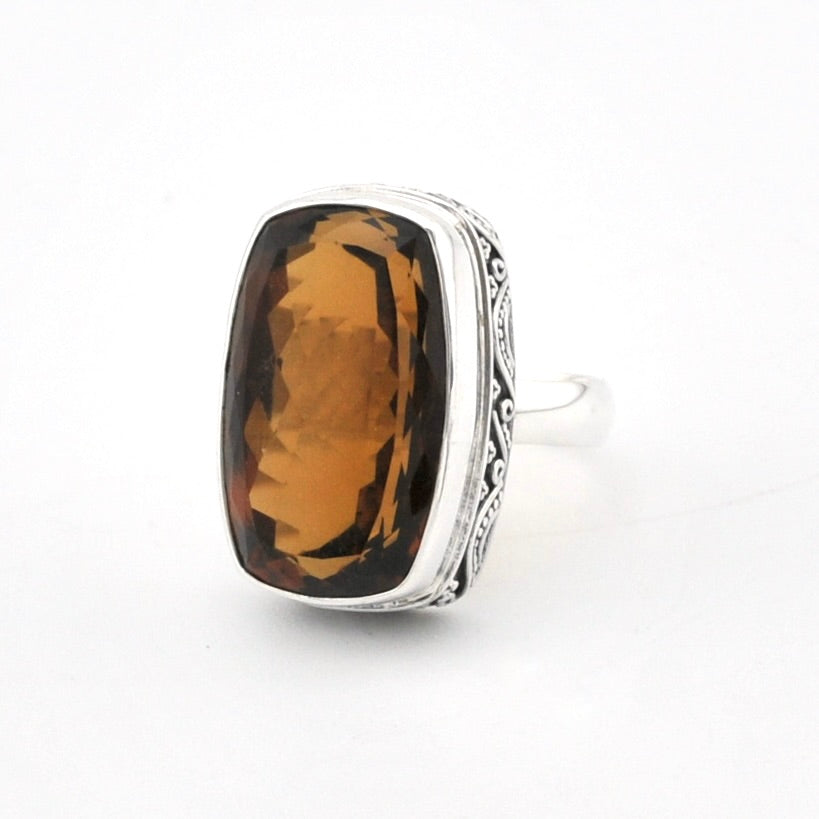 A silver ring featuring a large, cushion-cut brown smoky gemstone, photographed on a clean white background.