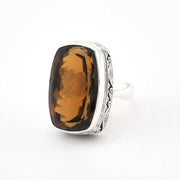 A silver ring featuring a large, cushion-cut brown smoky gemstone, photographed on a clean white background.