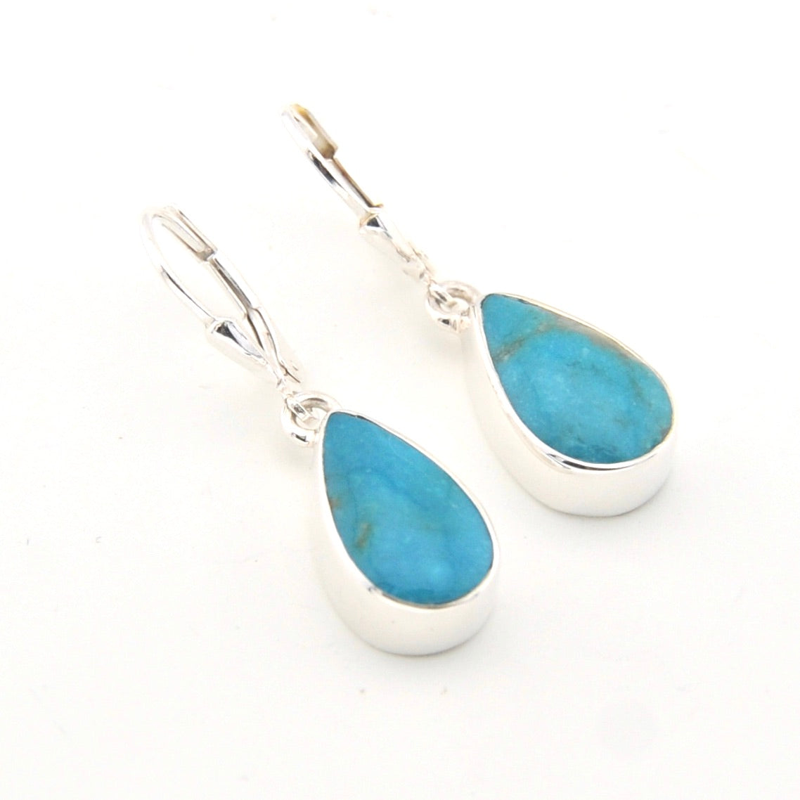 Teardrop-shaped turquoise earrings with silver settings on a white background