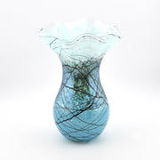A decorative glass vase with a flared, ruffled top and a rounded body, featuring a blue and white marbled pattern with black branch-like veining, set against a plain white background.