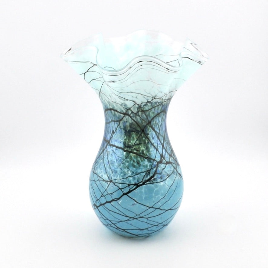 A decorative glass vase with a flared, ruffled top and a rounded body, featuring a blue and white marbled pattern with black branch-like veining, set against a plain white background.